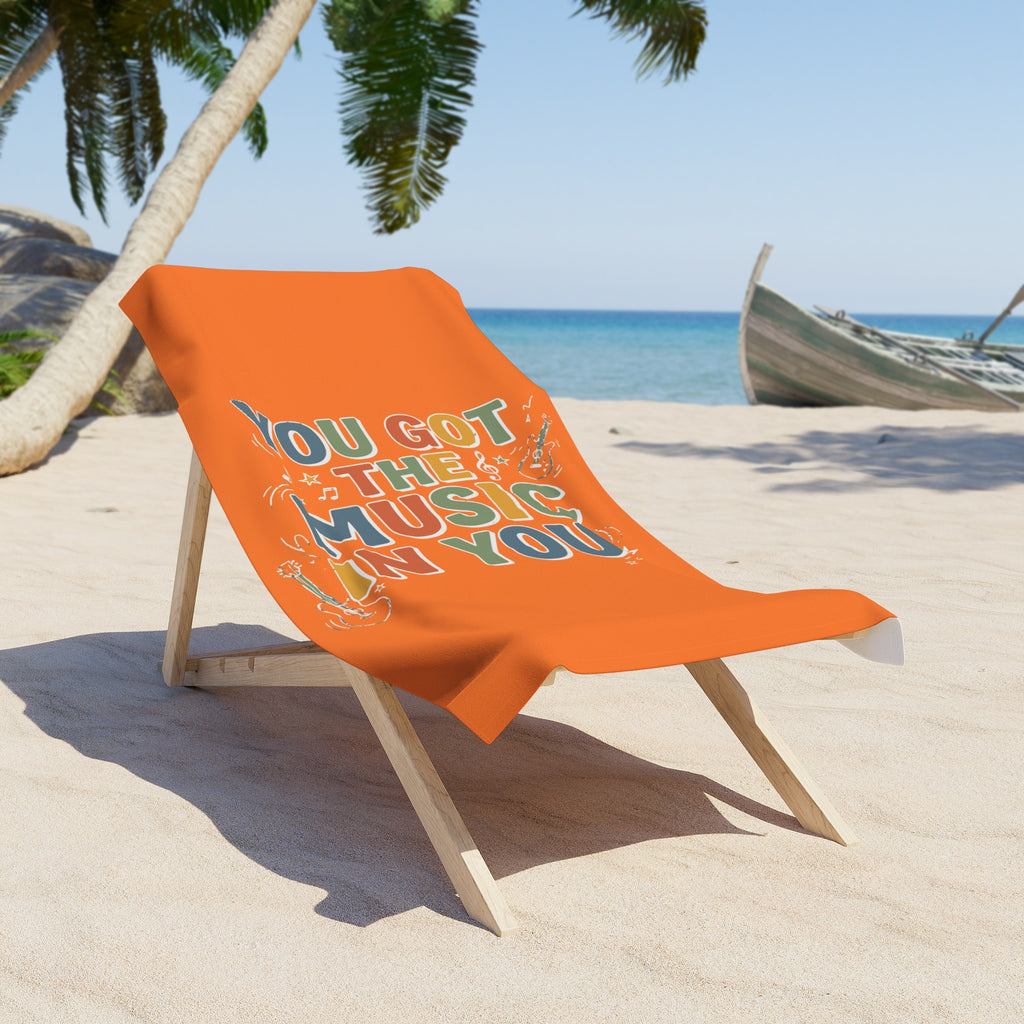 Orange beach towel with text on a wooden chair at a beach.