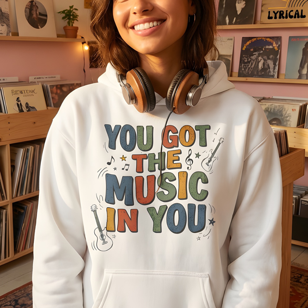 Person wearing a hoodie with 'You Got the Music in You' text in a room with records and posters.
