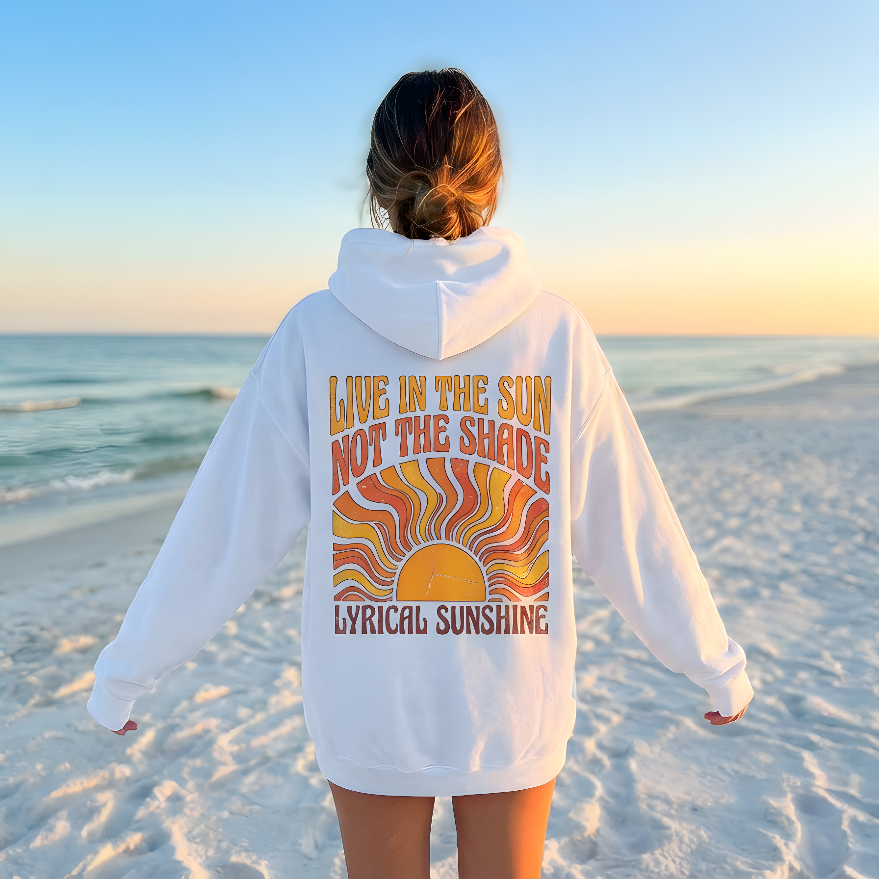 Person wearing a white hoodie with a colorful design on the beach