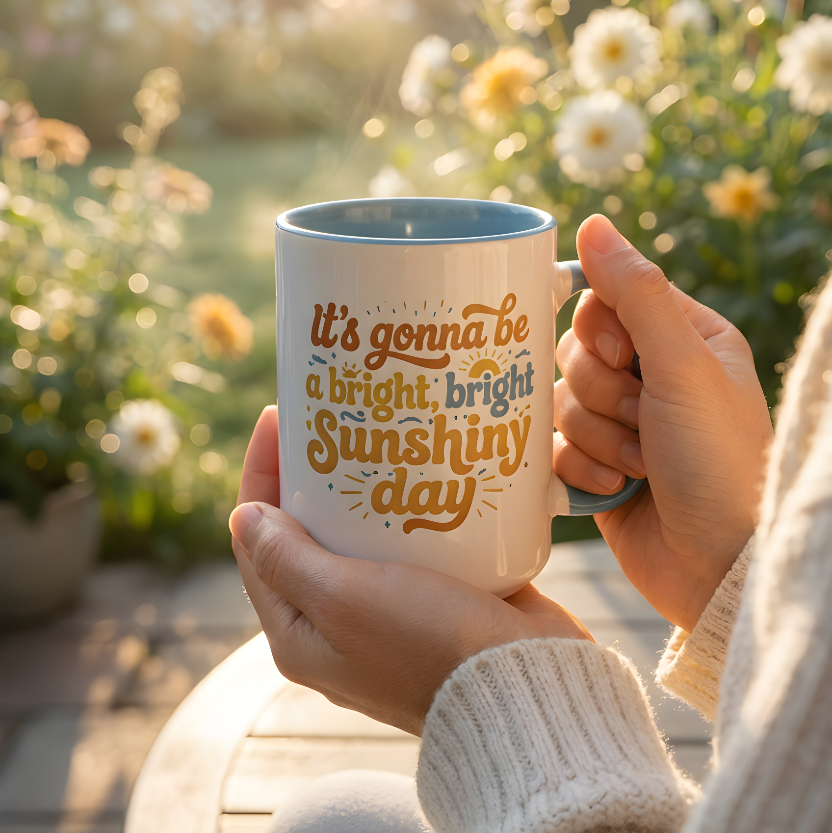 Person holding a mug with 'It's gonna be a bright, bright sunshiny day' text in a garden setting.