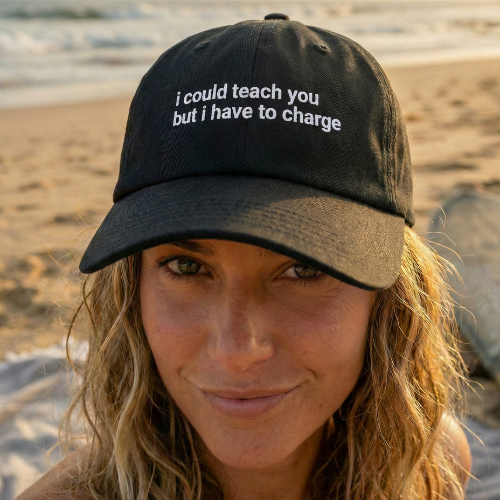 Person wearing a black cap with text on a beach