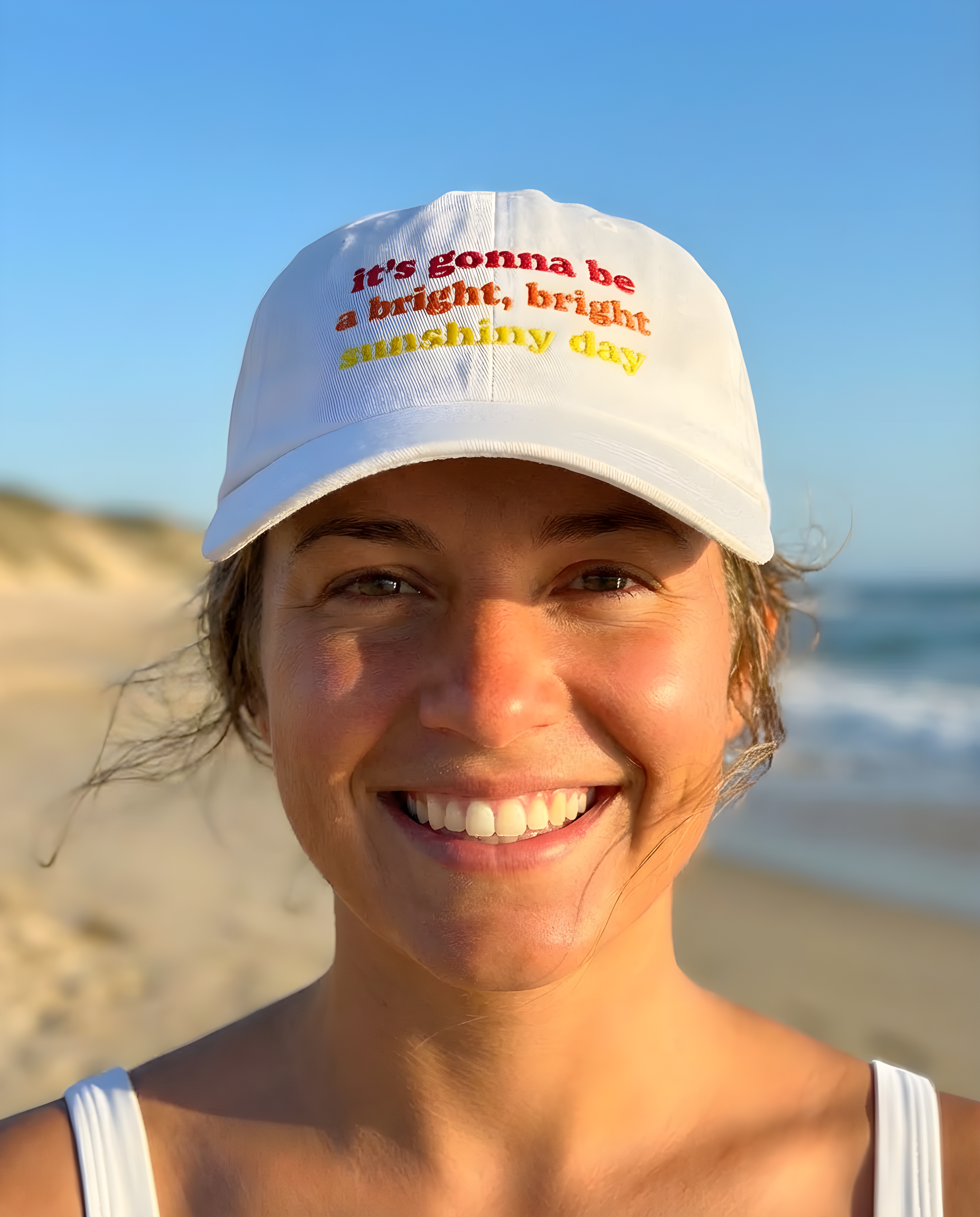 Person wearing a white cap with text on a beach