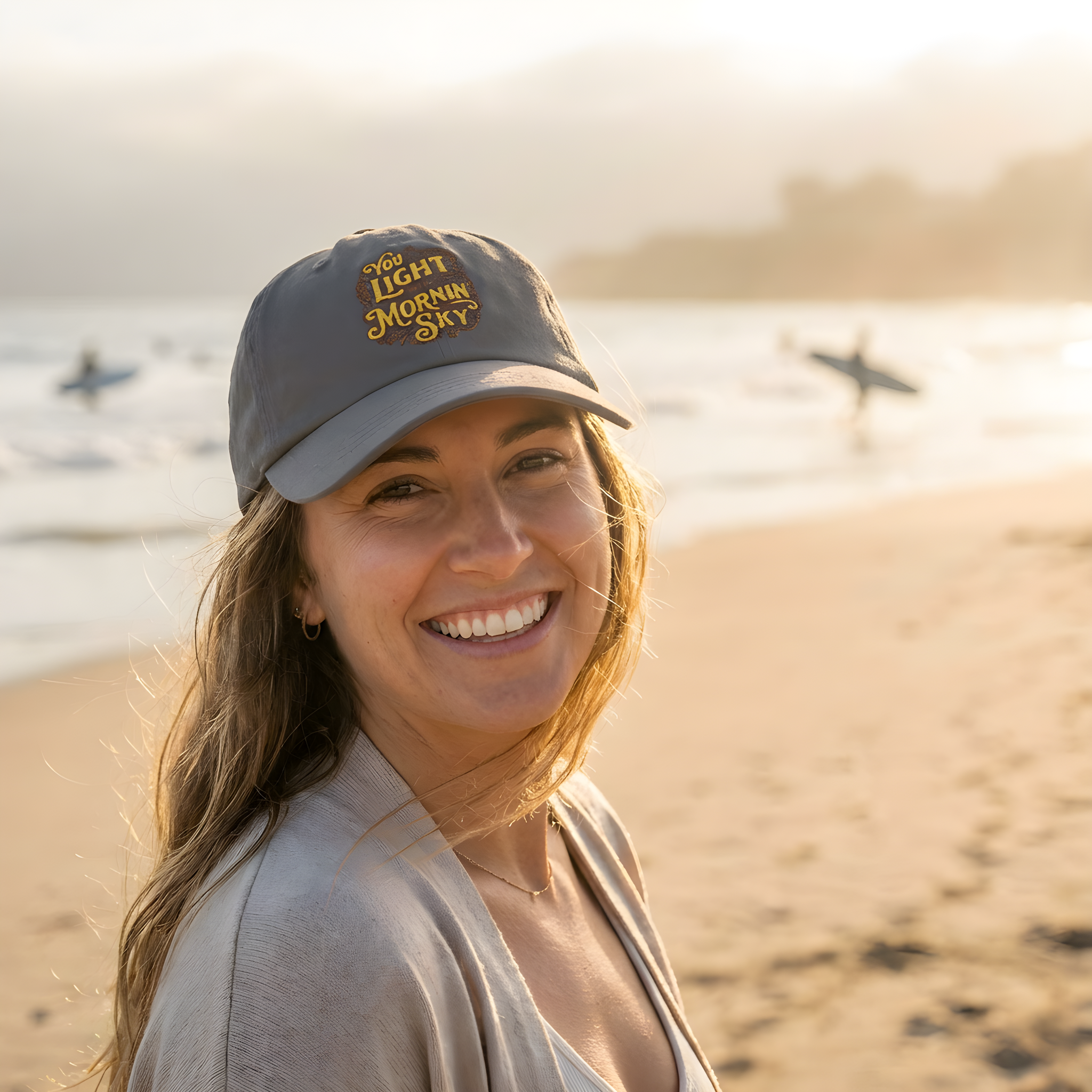 Woman wearing a cap with text on a beach at sunset