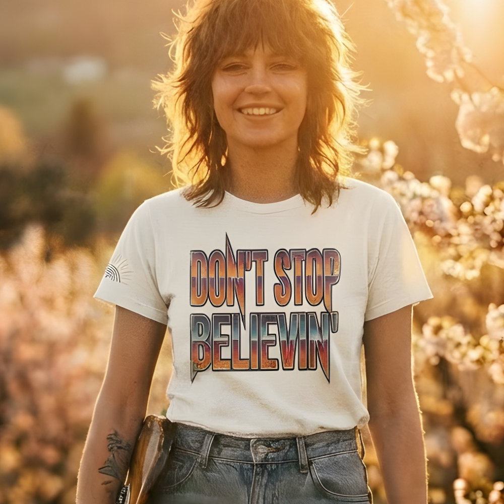 Person wearing a 'Don't Stop Believin'' t-shirt in a scenic outdoor setting