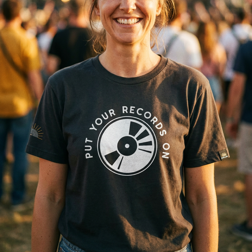 Woman wearing a black t-shirt with a graphic design and text, standing in a crowd at an event.