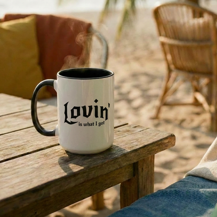 Mug with 'Lovin is what I got' text on a wooden table by a beach.