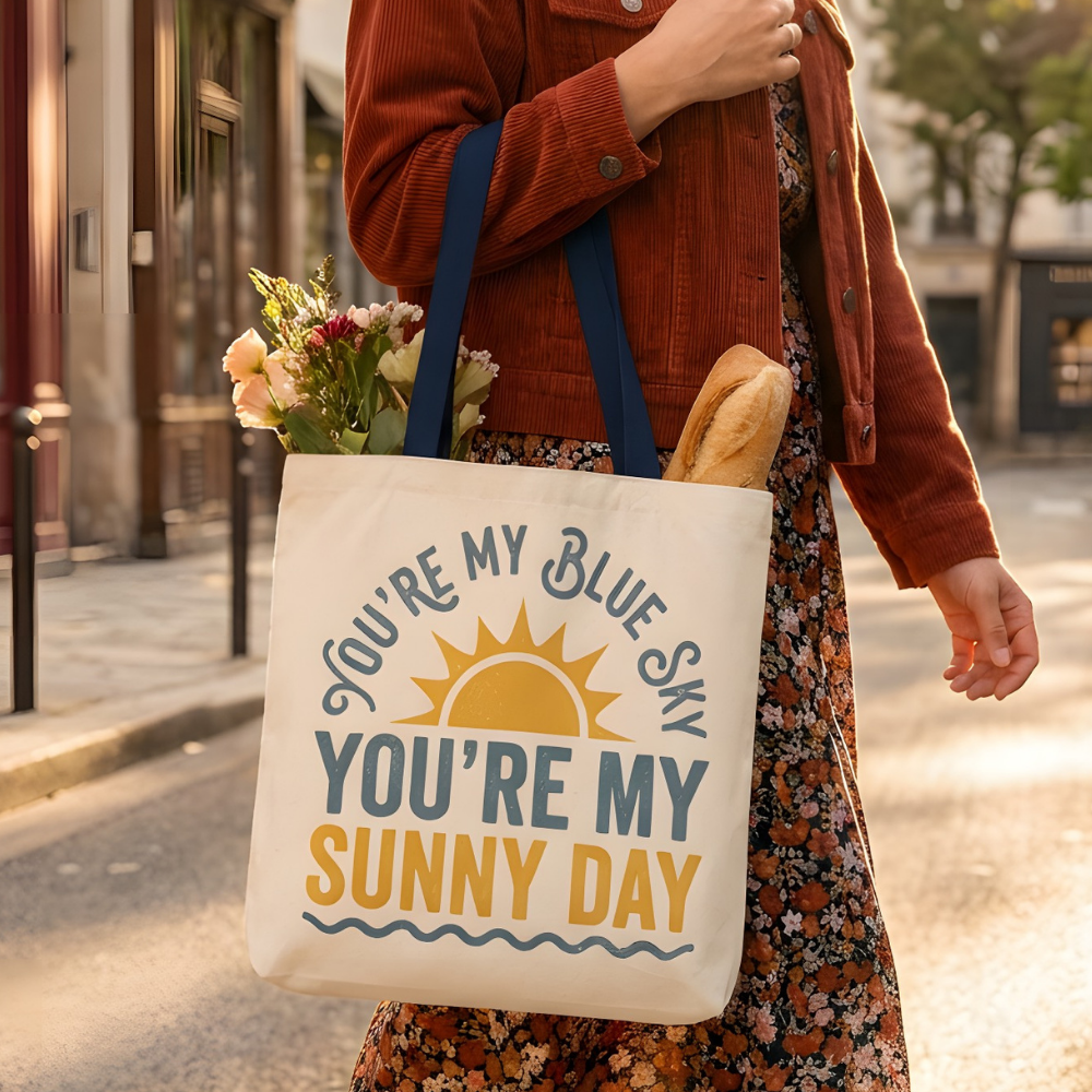 Woman holding a tote bag with a motivational quote on a city street.