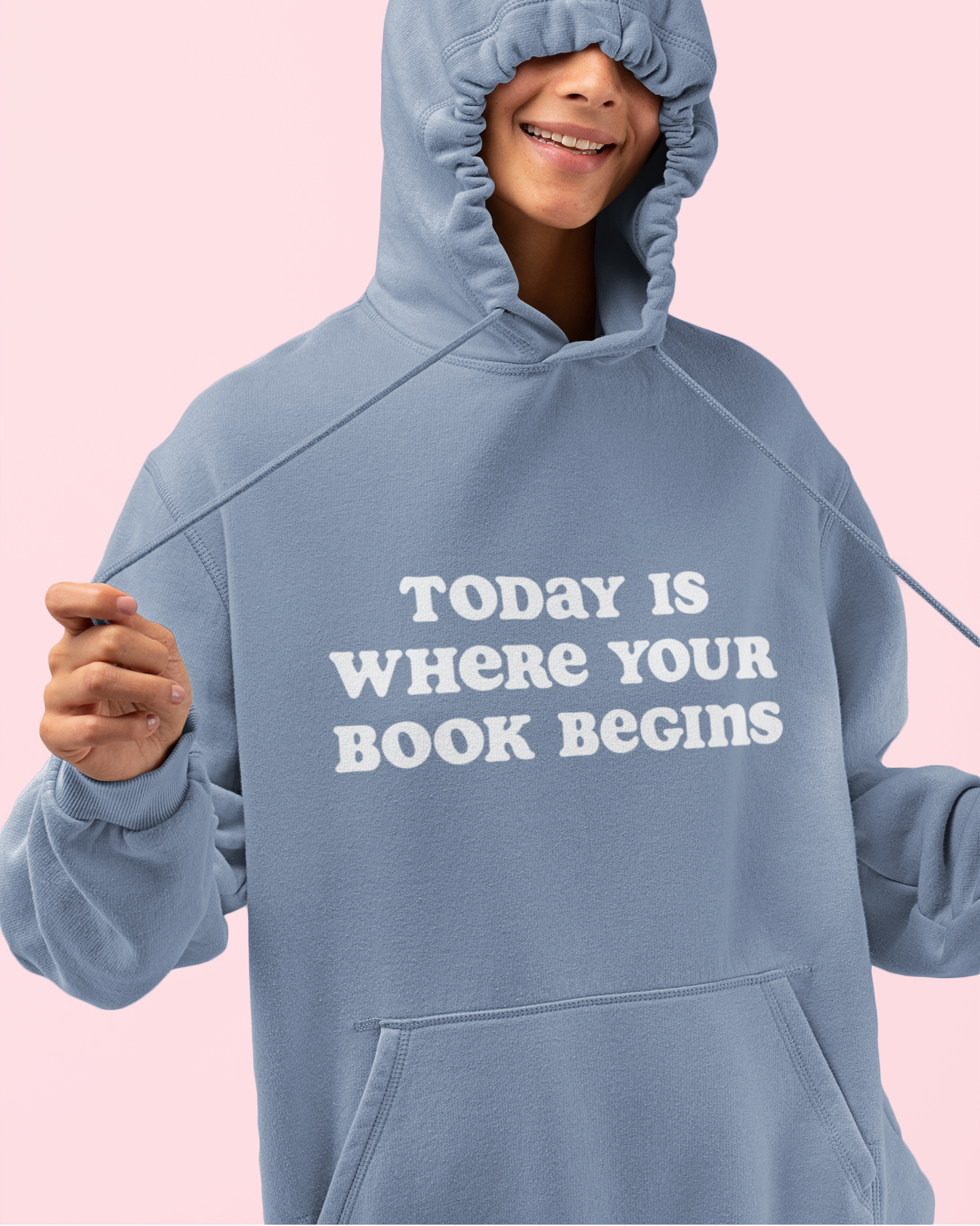 Person wearing a blue hoodie with text on a pink background