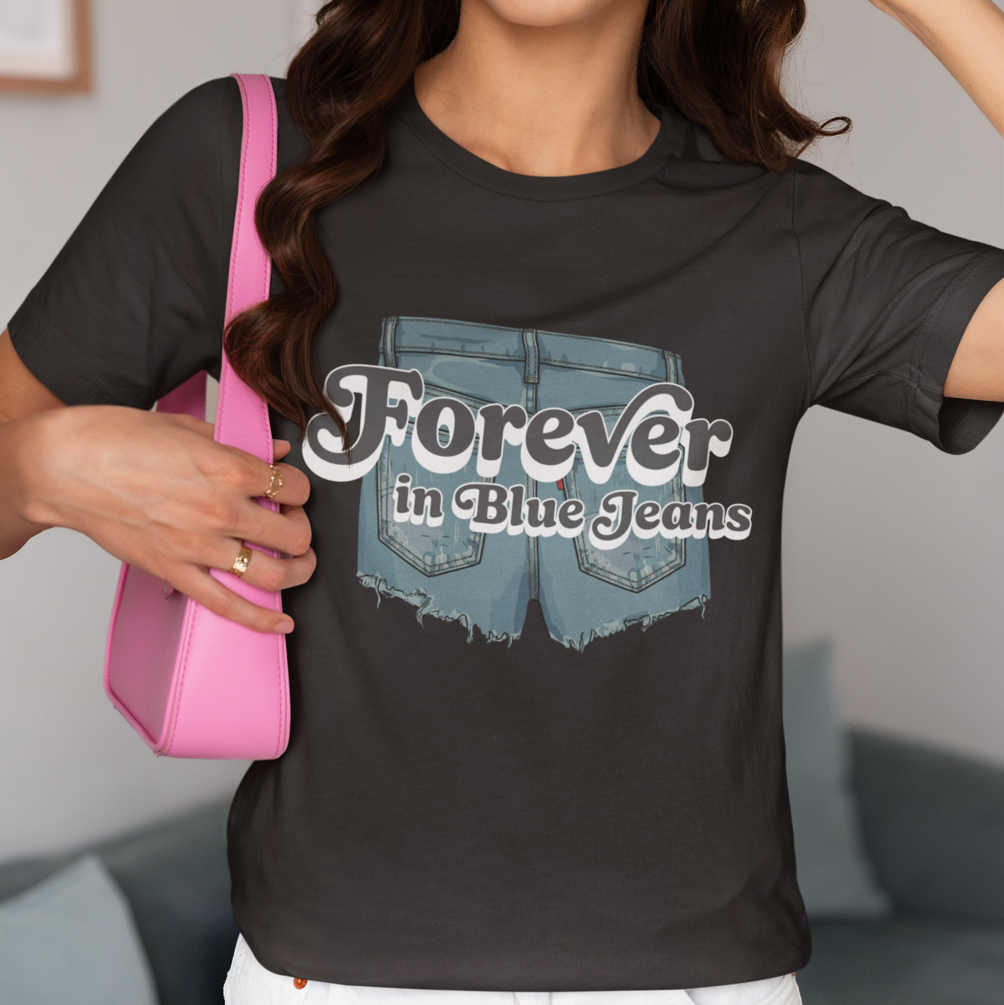 Person wearing a black t-shirt with 'Forever in Blue Jeans' design, holding a pink bag.