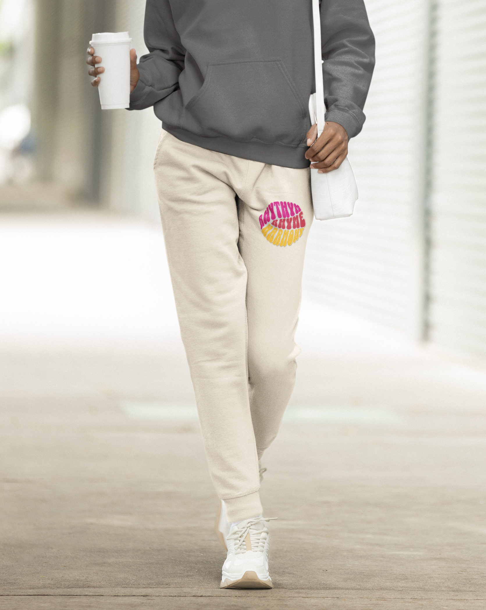 Person wearing a gray hoodie and beige pants walking outdoors.