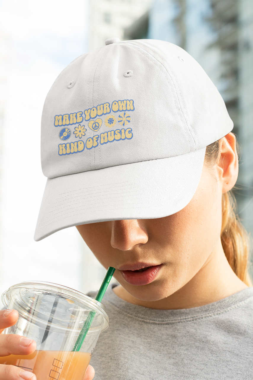 Person wearing a white cap with text, drinking from a clear cup with a green straw in an urban setting.