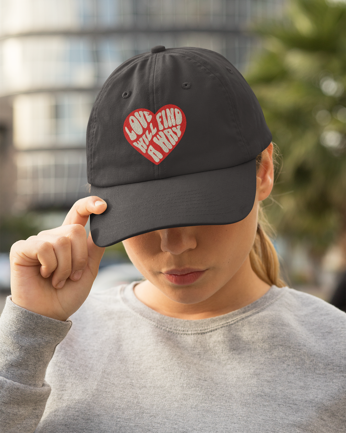 Person wearing a black cap with a red heart design outdoors