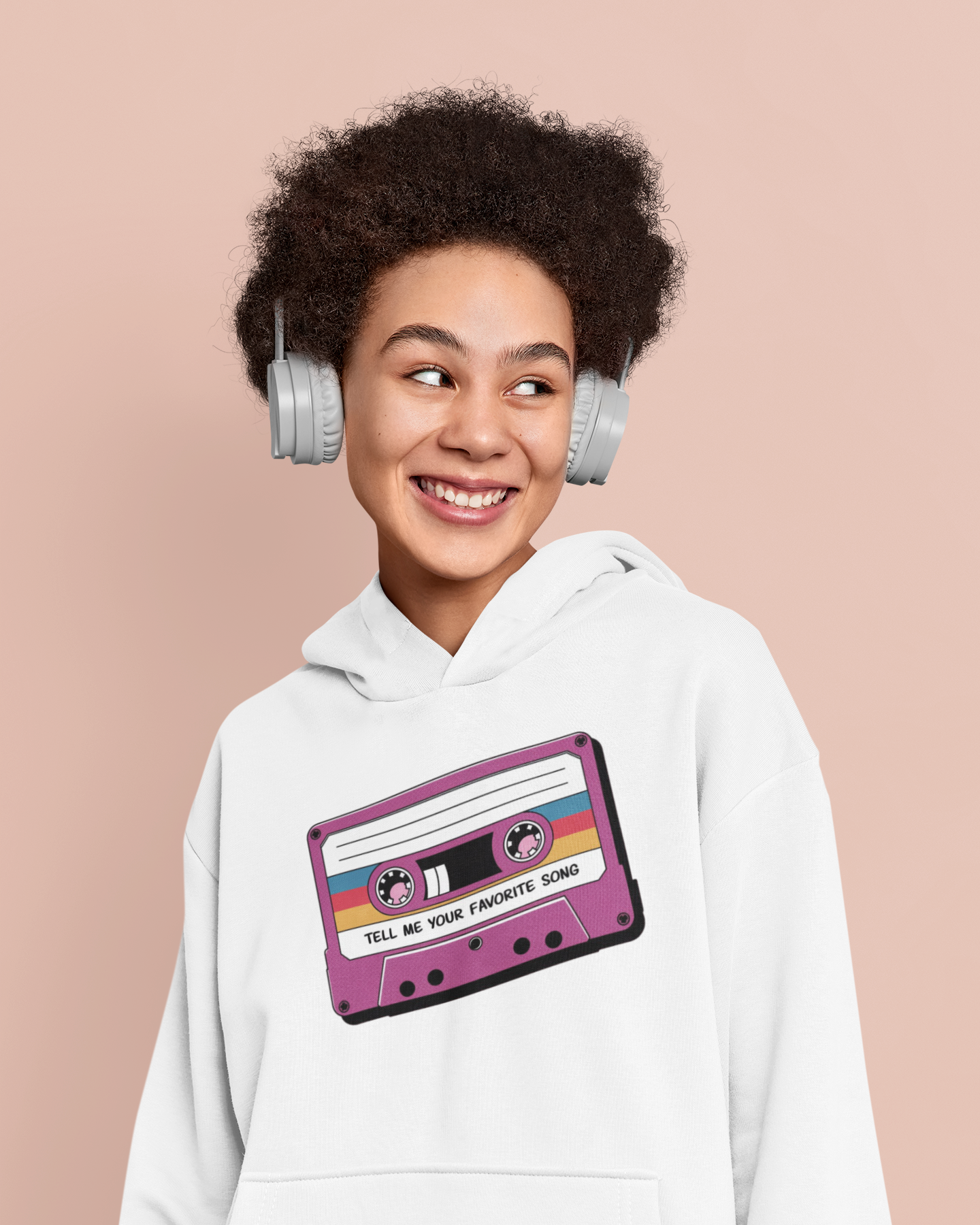 Person wearing a white hoodie with a cassette tape design, smiling against a beige background