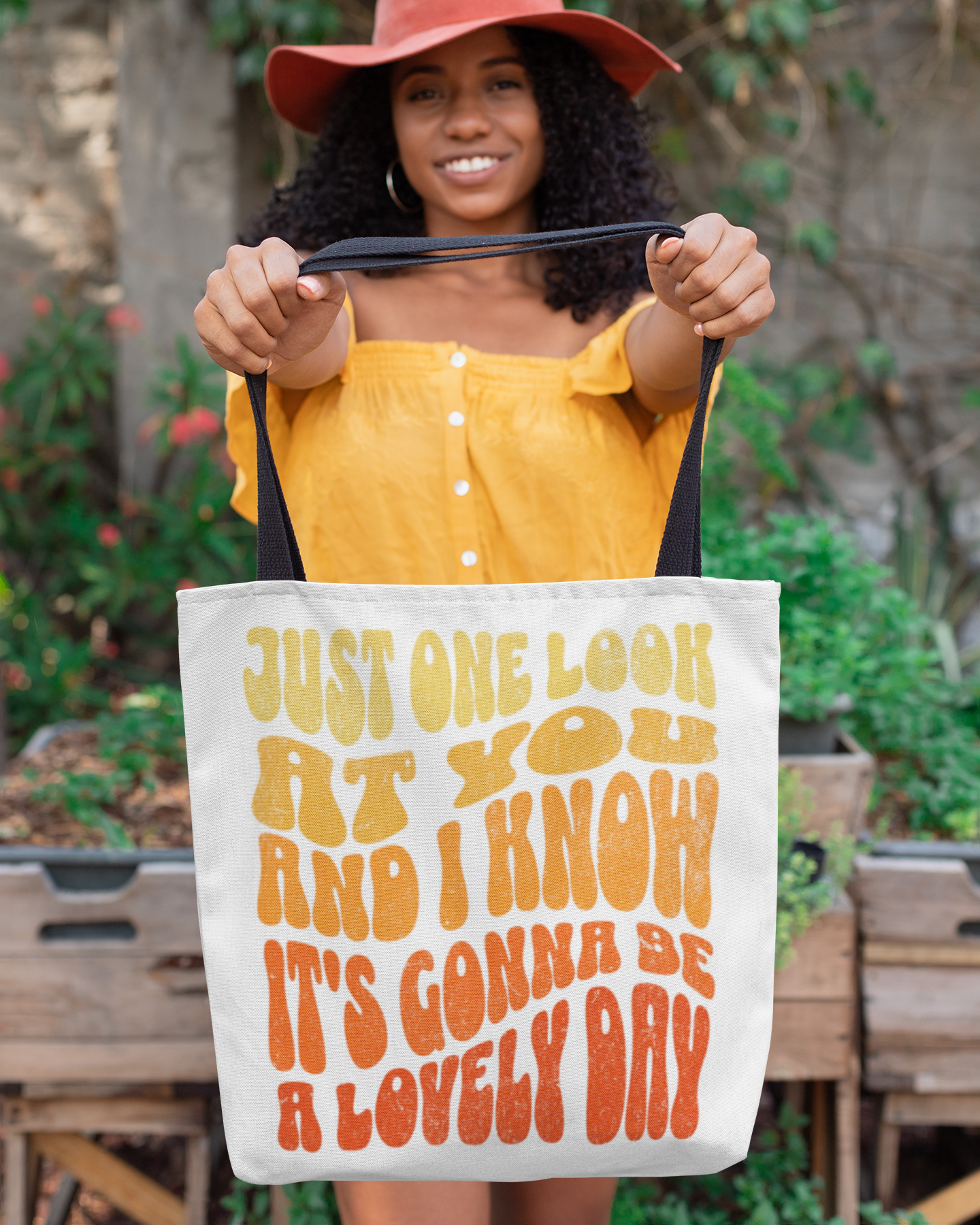 Woman holding a tote bag with text in an outdoor setting