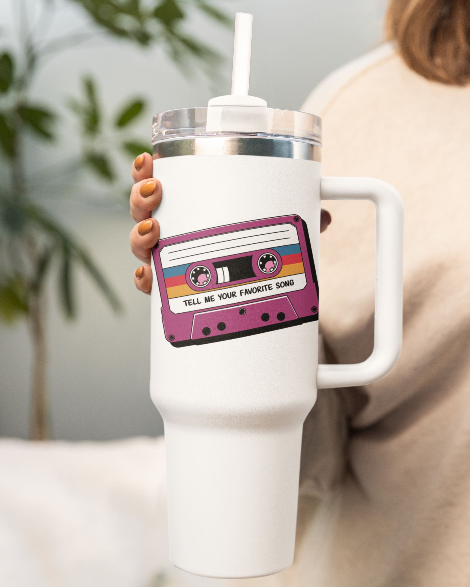 White mug with a cassette tape design held by a person indoors.