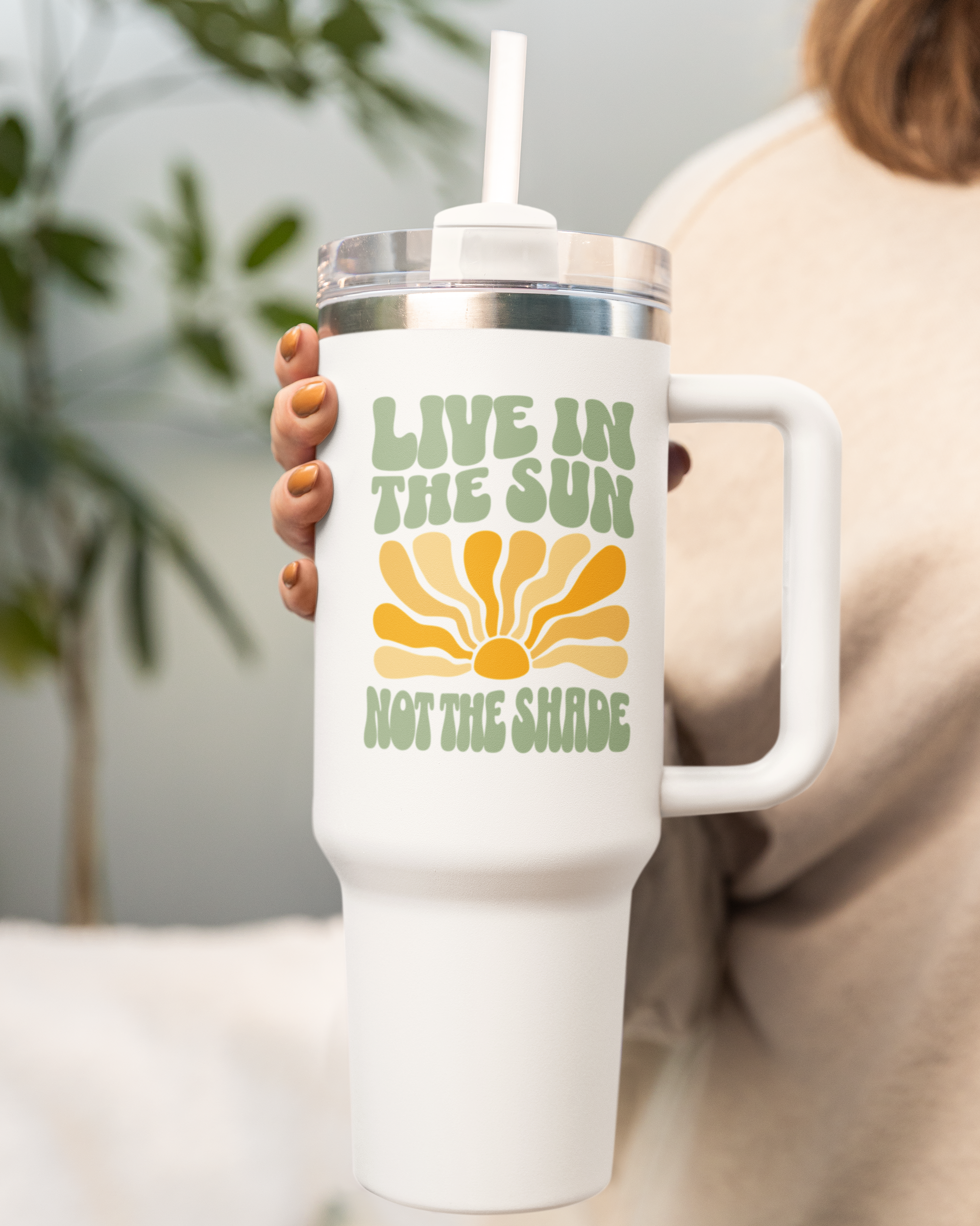White tumbler with 'Live in the Sun Not the Shade' design held by a person.