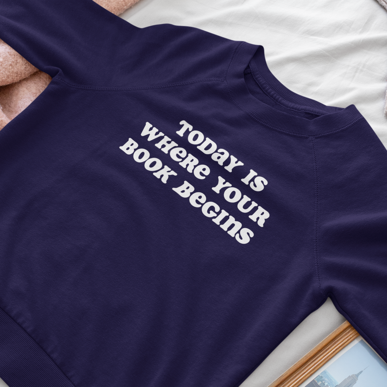 Navy blue shirt with text 'Today is where your book begins' on a white surface.