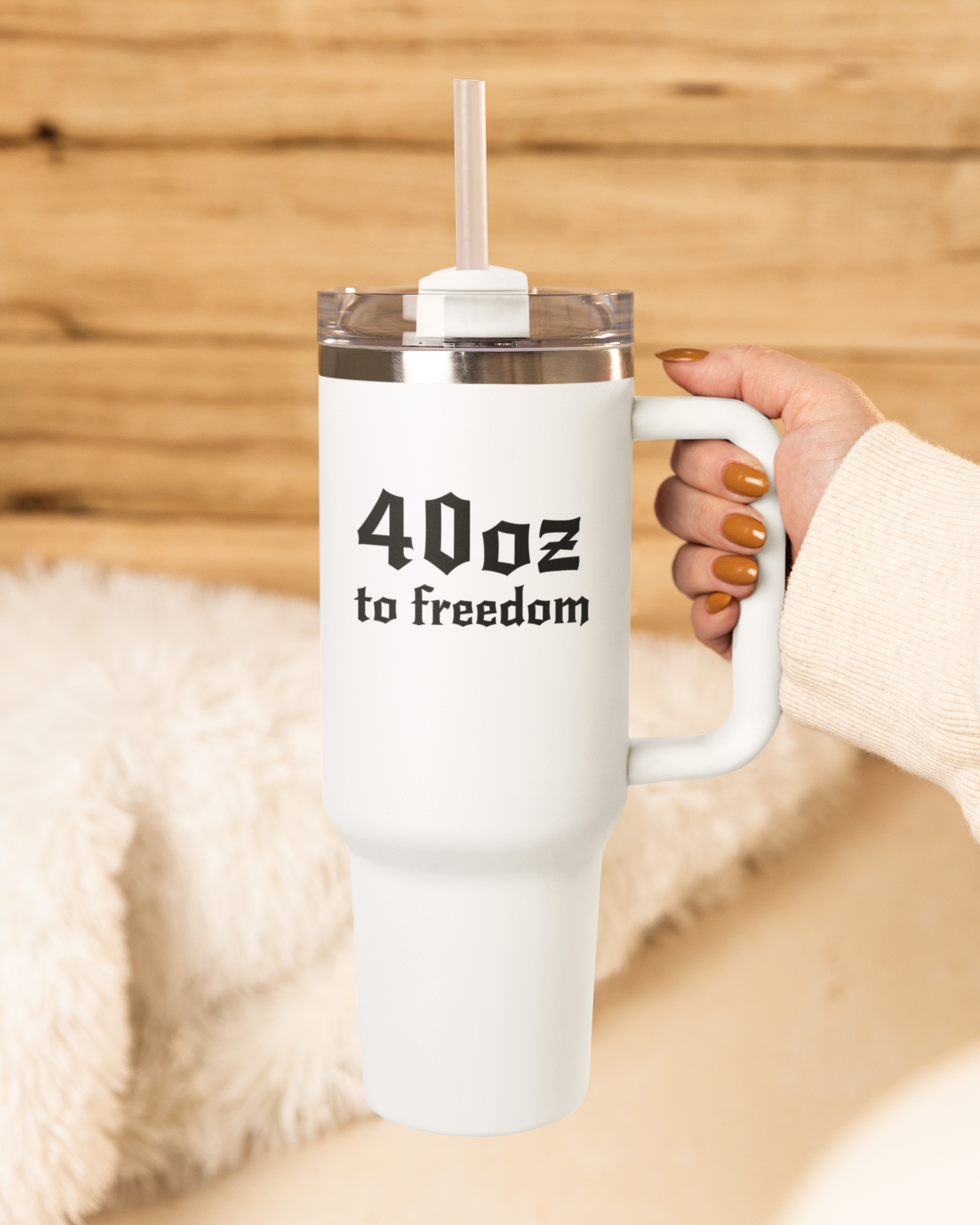 White mug with '40 oz to freedom' text held by a person against a wooden background