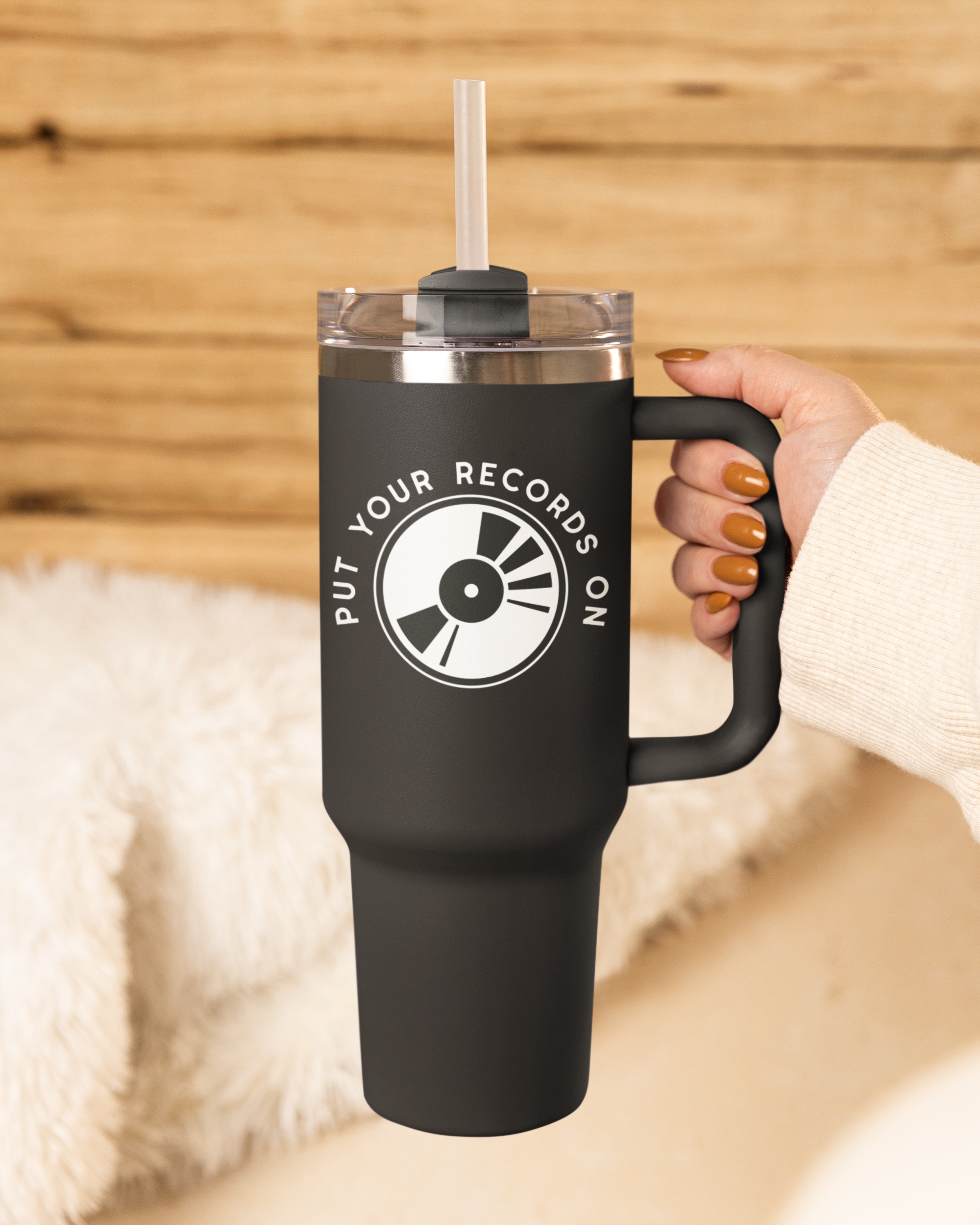 Black mug with 'Put Your Records On' design held by a hand against a wooden background