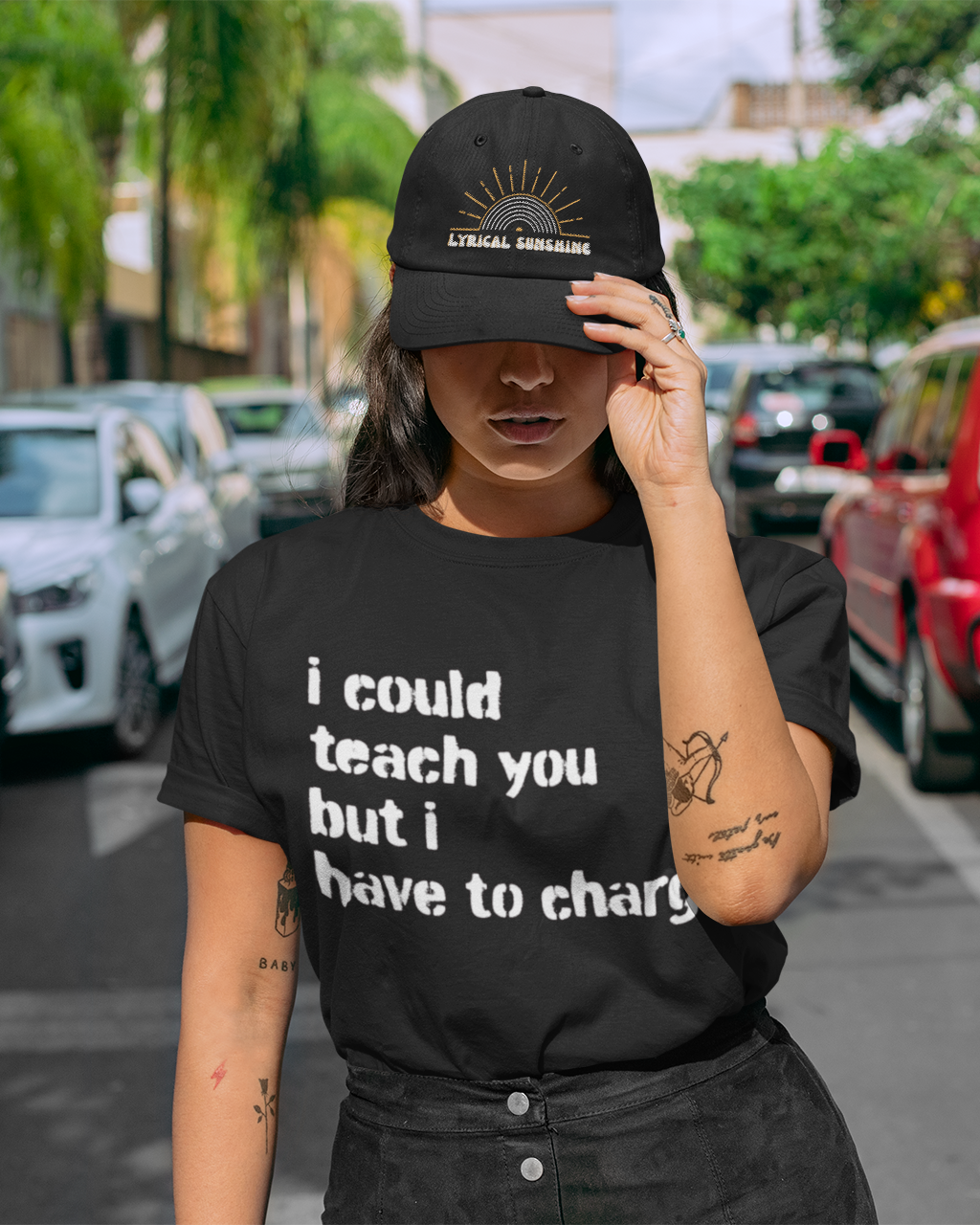 Person wearing a black t-shirt with text and cap on a street.