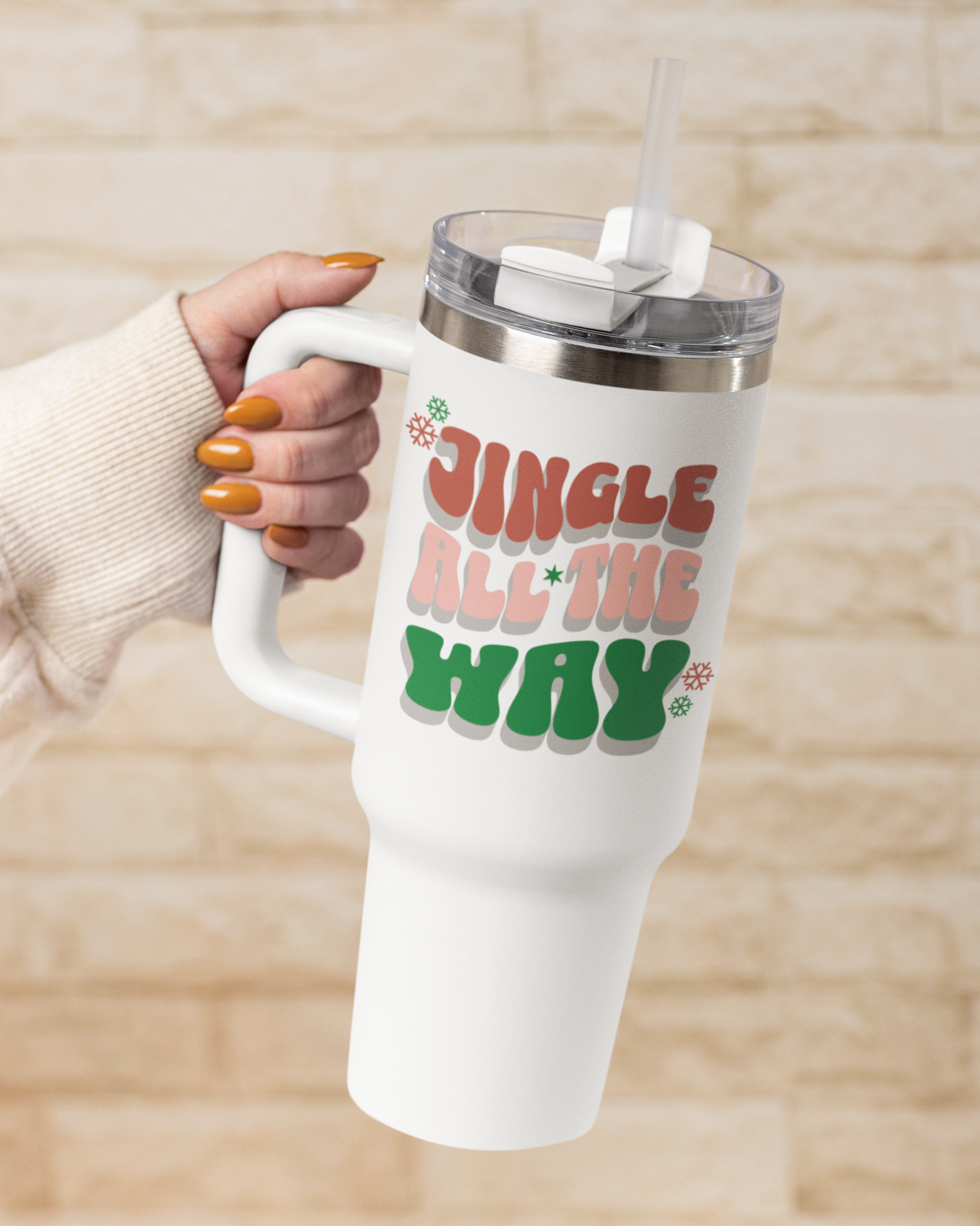 White tumbler with 'Jingle All the Way' text held by a person against a beige background
