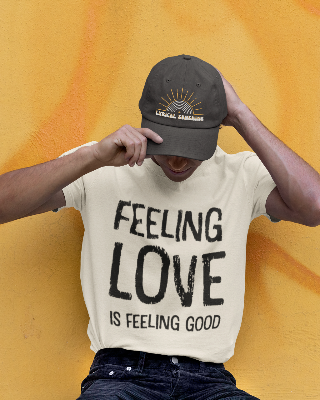 Person wearing a t-shirt with 'Feeling Love is Feeling Good' text and a cap against an orange background