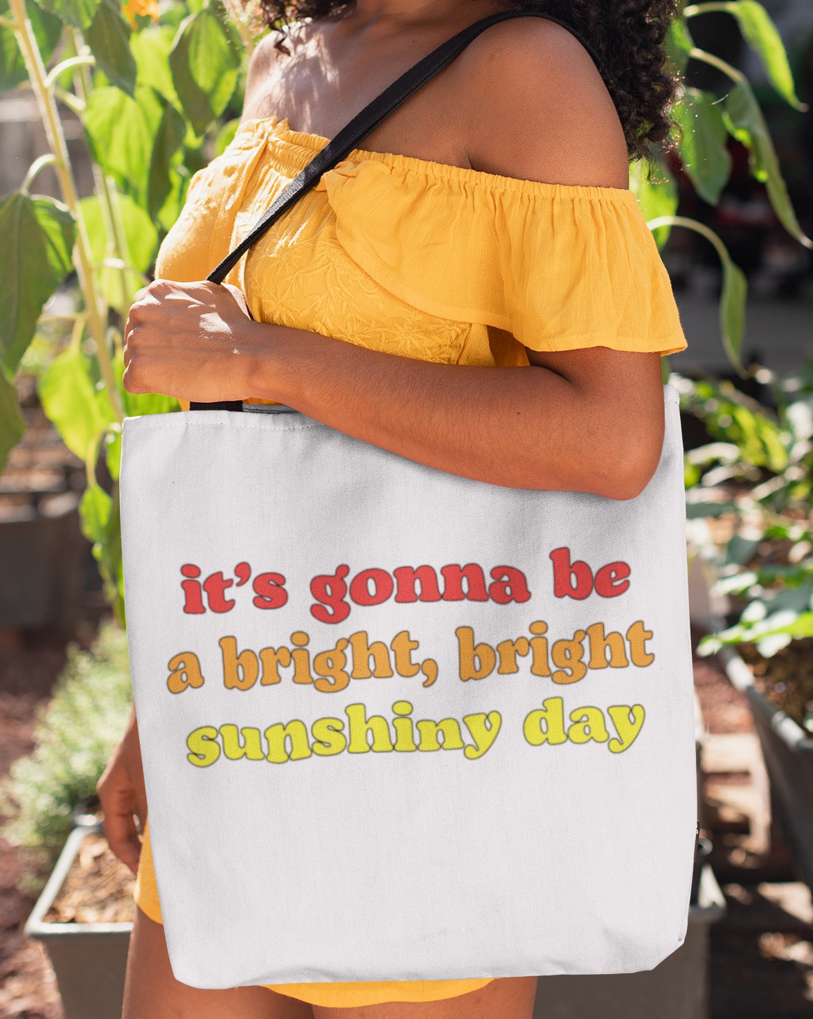 Woman holding a tote bag with text in a garden setting